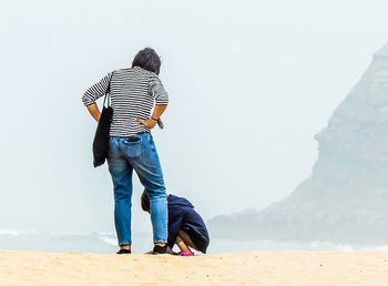 Rear view of man standing on land against sky