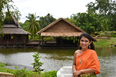 Portrait of woman wearing traditional clothing standing against lake