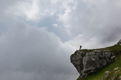 Low angle view of person on cliff against sky