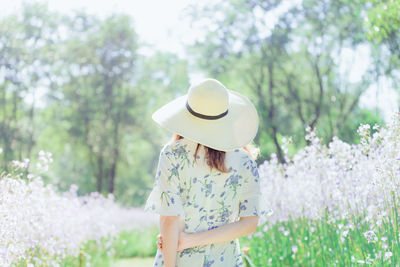 Midsection of woman standing by flowering plants on field