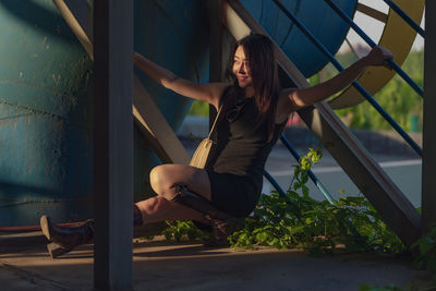 Full length of young woman sitting on railing