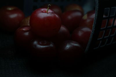 Closeup of fresh red juicy plums on the basket with droplets of water on a black background. 