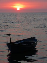 Boat moored on sea against sky during sunset