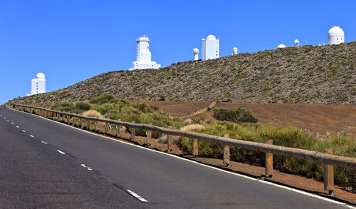 Road leading towards lighthouse against clear blue sky