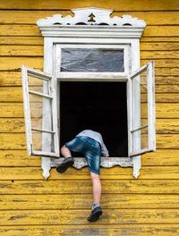 Full length of kid climbing through window