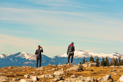 Rear view of people standing on mountain during winter