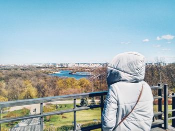 Rear view of woman with umbrella against sky