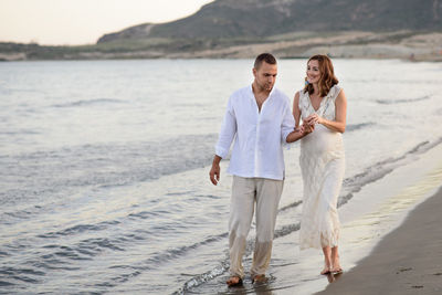 Mid adult couple walking on shore at beach