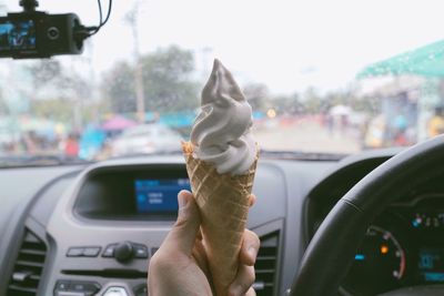 Close-up of person holding ice cream in car