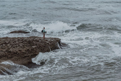 Man standing by sea on rock