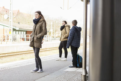 Young woman with friends waiting for train at station