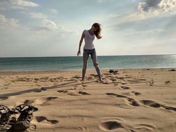 Full length of woman standing at beach against sky