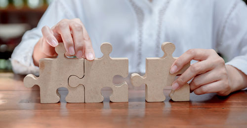 Midsection of woman holding puzzle on table