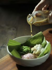 Cropped hand of person pouring liquid palm sugar for topping putu mayang cake