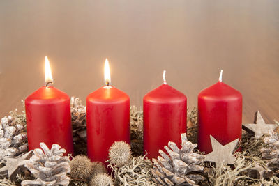 Close-up of red lit candles amidst christmas decorations at night