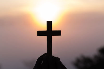 Silhouette cross against sky during sunset