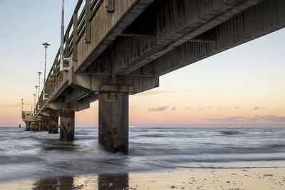 Bridge over sea against sky during sunset