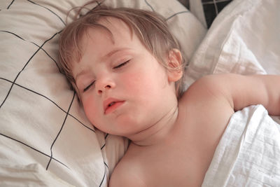 Close-up of cute baby sleeping on bed