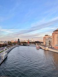 Buildings by river against sky