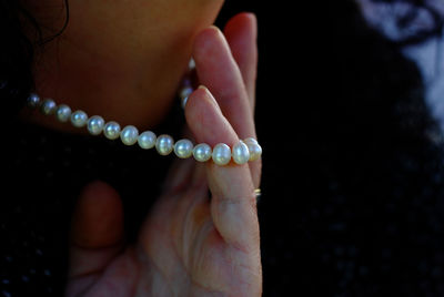 Close-up of woman holding pearl necklace