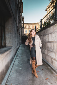 Portrait of woman standing on footpath in city