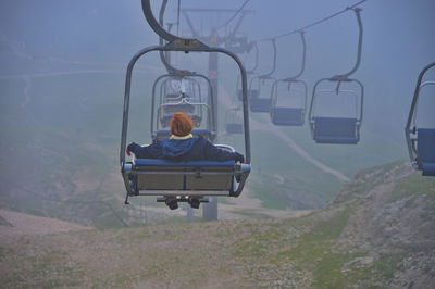 Senior woman sitting on cable car while riding over scenic landscape of italian dolomites