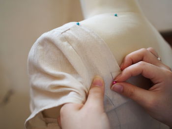 Close-up of woman hands pushing straight pins in mannequin