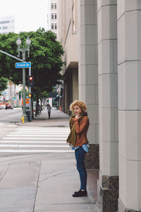 Woman standing on footpath against building