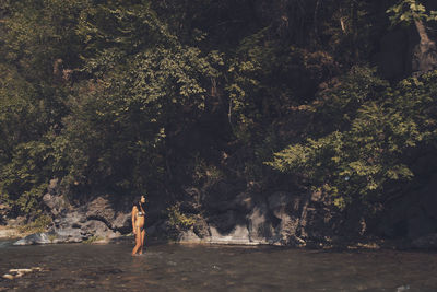 Woman standing by trees in forest