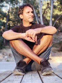 Full length of man sitting on wood