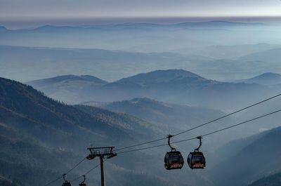 Overhead cable car over mountains against sky