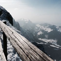 Wooden fence against snowcapped mountains during winter