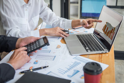 Midsection of business people working on table