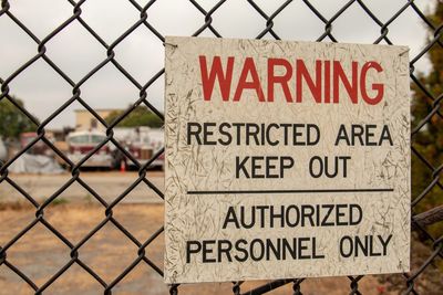 Close-up of warning sign on chainlink fence