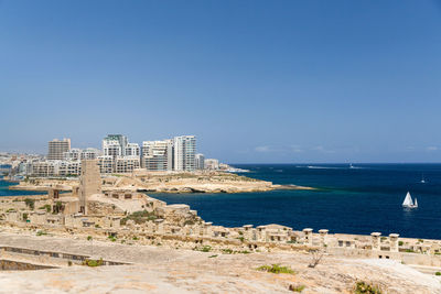 Buildings by sea against clear sky