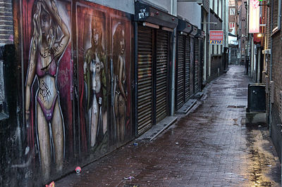 Wet footpath amidst buildings in city