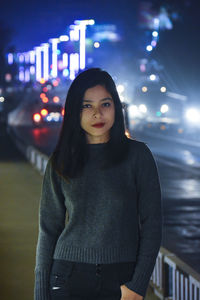 Portrait of smiling young woman standing at night