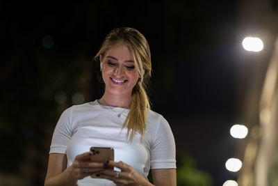 Woman using a smartphone at night time on the street. mobile phone, technology, urban .