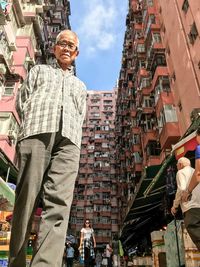 Low angle view of man standing on street in city against sky