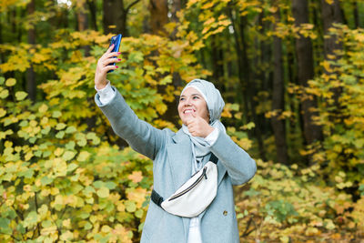 Full length of man photographing with mobile phone in park