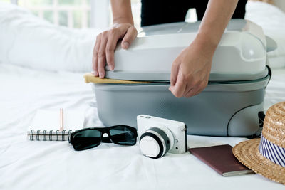 Midsection of woman packing suitcase on bed