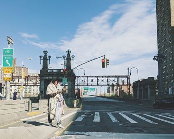 People standing on road in city against sky