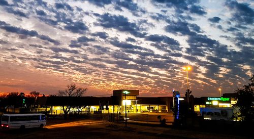 Illuminated city against sky at sunset