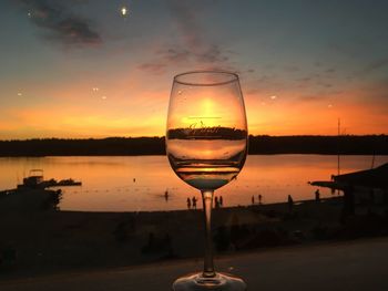 Wine glass on table against sky during sunset