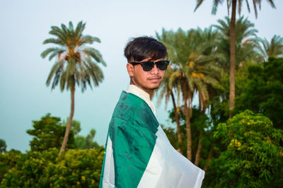 Portrait of young man standing against trees