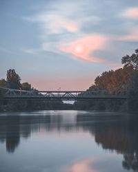 Arch bridge over river against sky during sunset