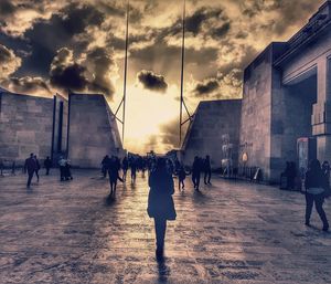 People walking on street in city at sunset