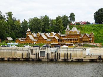 Houses by river and buildings against sky