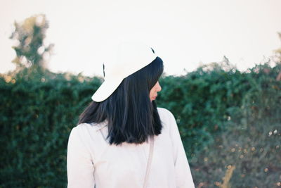 Young woman wearing cap against plants