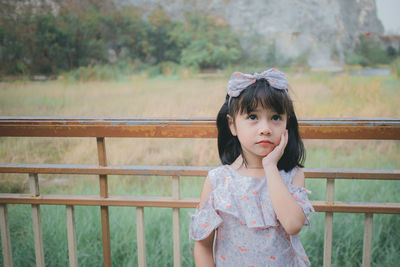 Girl looking away while standing against railing